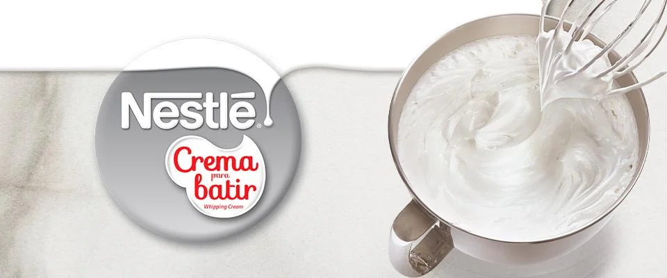 Crema para batir NESTLÉ® sobre un tazón plateado acompañado del logo de la marca