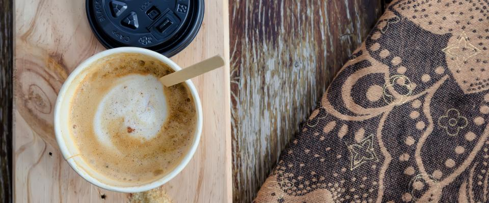Una taza de cappuccino espumoso en plano cenital sobre una mesa de madera