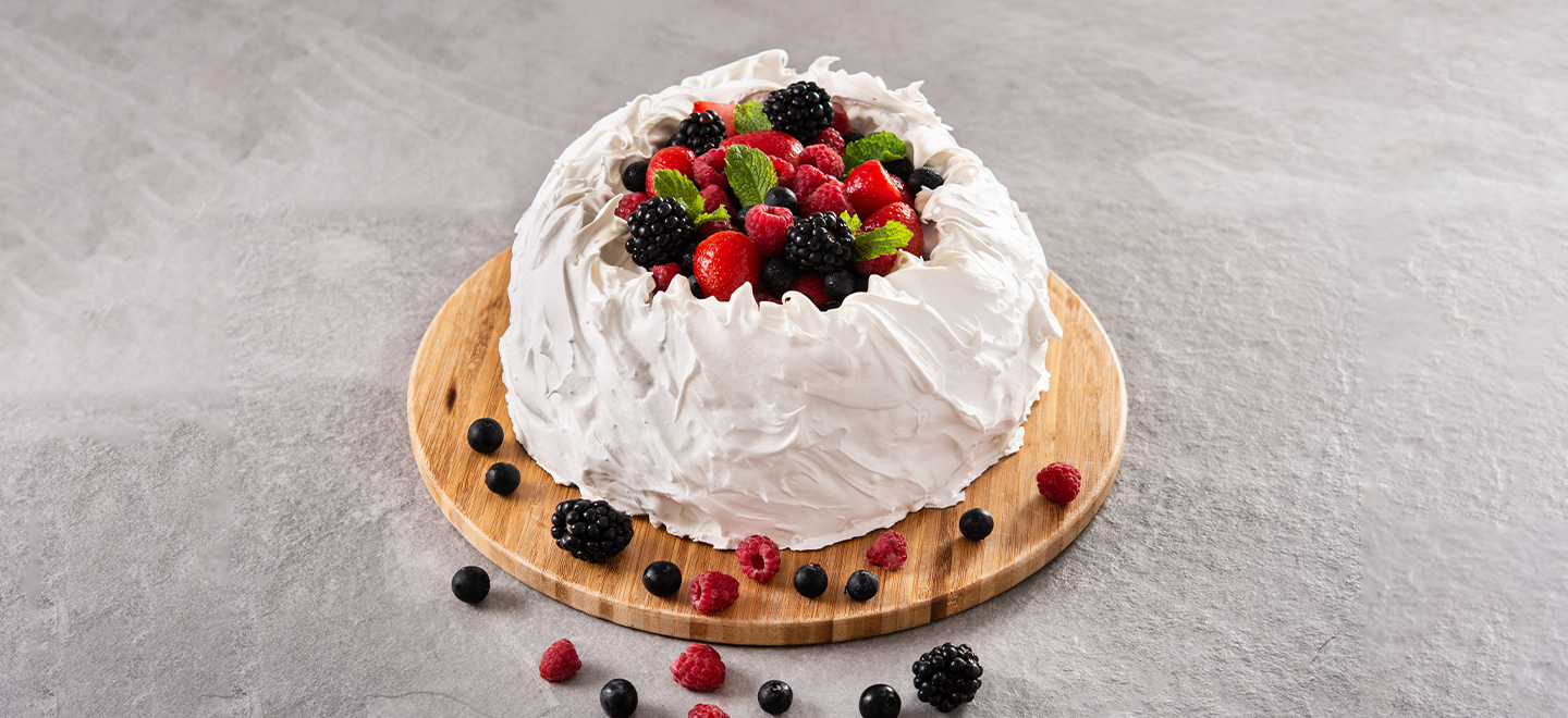 Pavlova con merengue y frutas del bosque sobre base redonda de madera