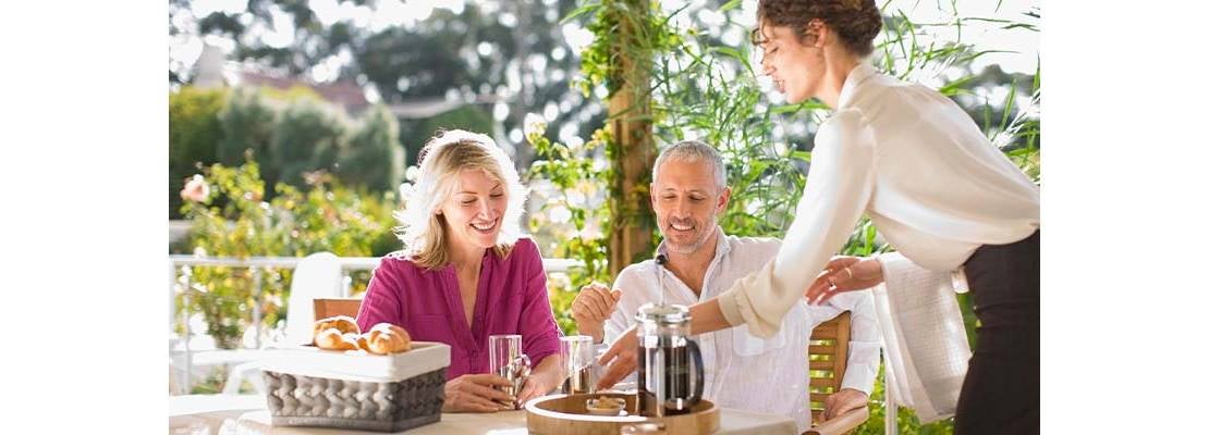 Mesera atendiendo a una pareja en uan restaurante al aire libre