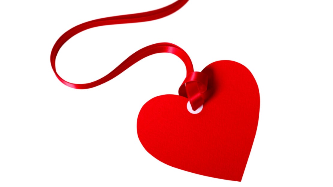 Corazón hecho en papel y con listón para decorar una cena romántica