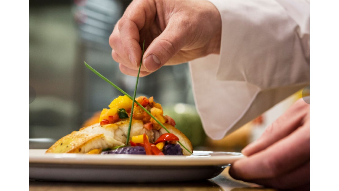 Chef decorando el plato fuerte de una cena romántica