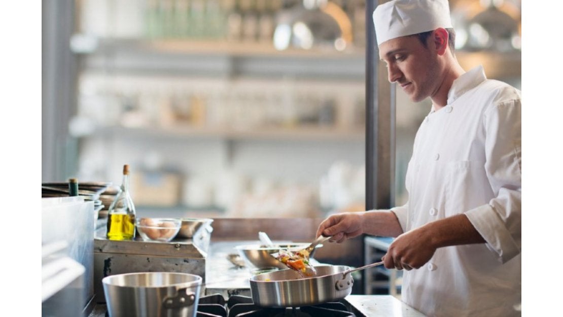 Un chef uniformado preparando una receta en su cocina profesional