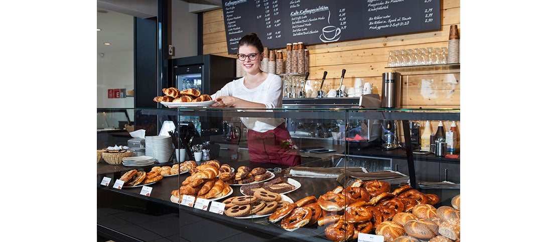 Mujer atendiendo su cafetería y a sus comensales