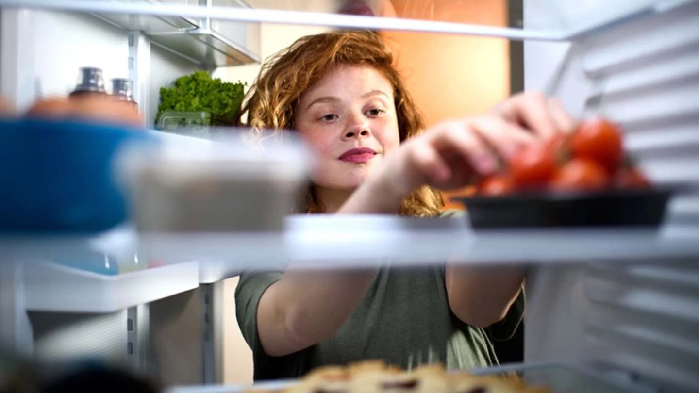 Mujer almacena tomates en el refrigerador junto a otros alimentos