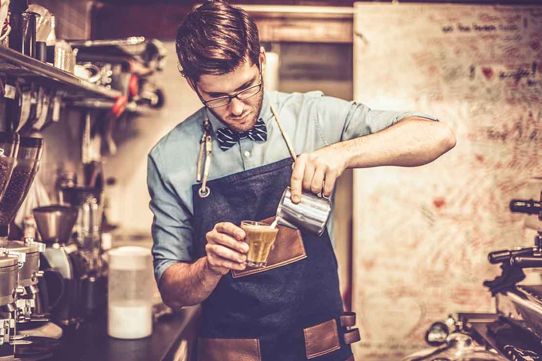 Experto en café prepara en una cafetería una bebida usando latte art, el cual aprendió en Nestlé Jóvenes Baristas