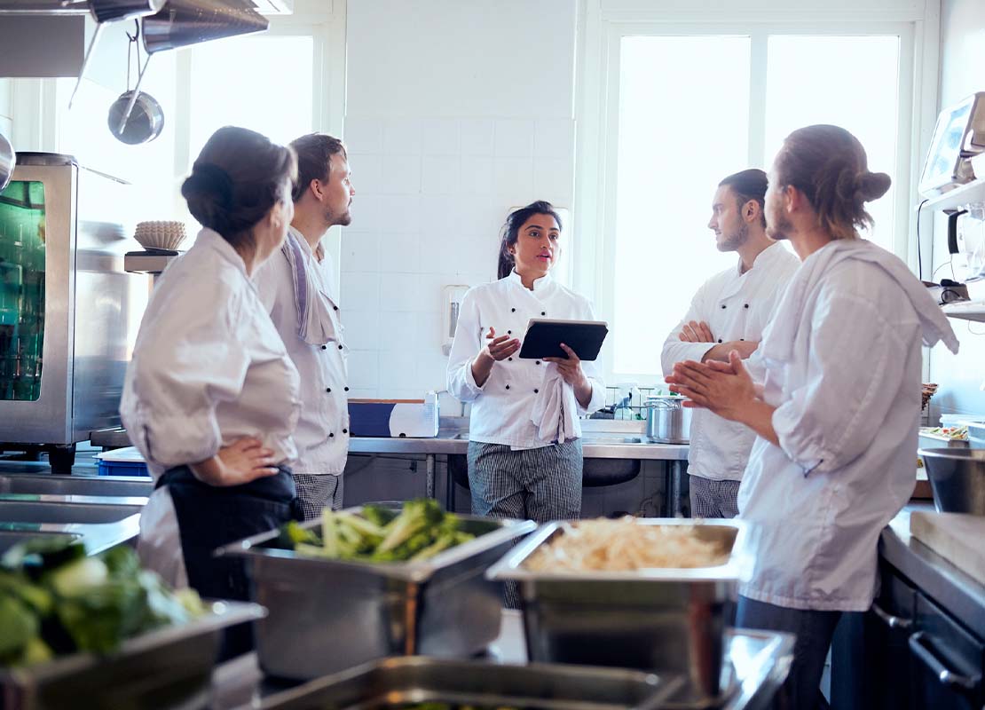 Chef ejecutiva realiza una capacitación de personal a cuatro chefs y asistentes en la cocina del restaurante