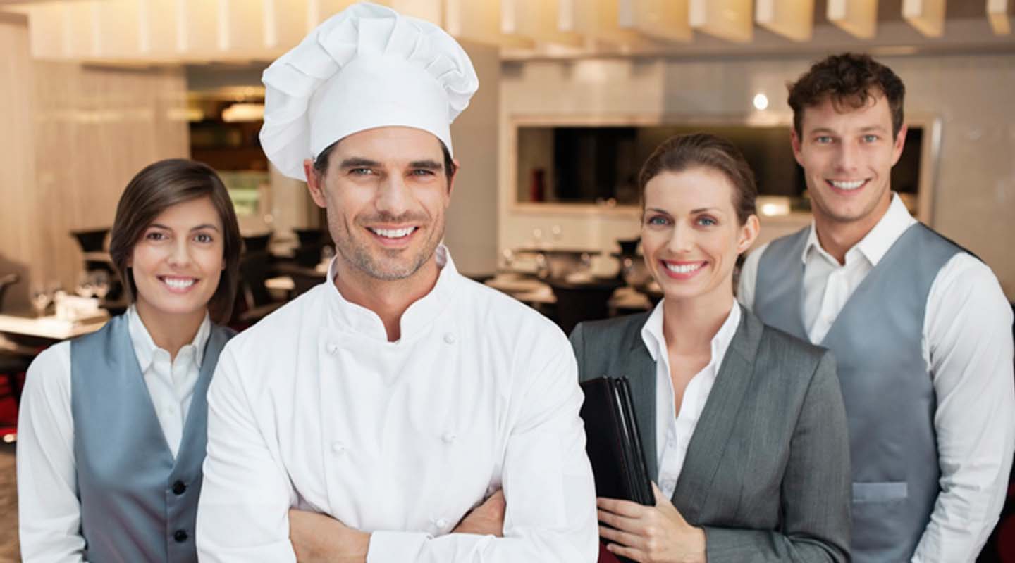 Dos camareros, una gerente de restaurante y un chef que recibieron capacitación de personal para tener un equipo eficiente