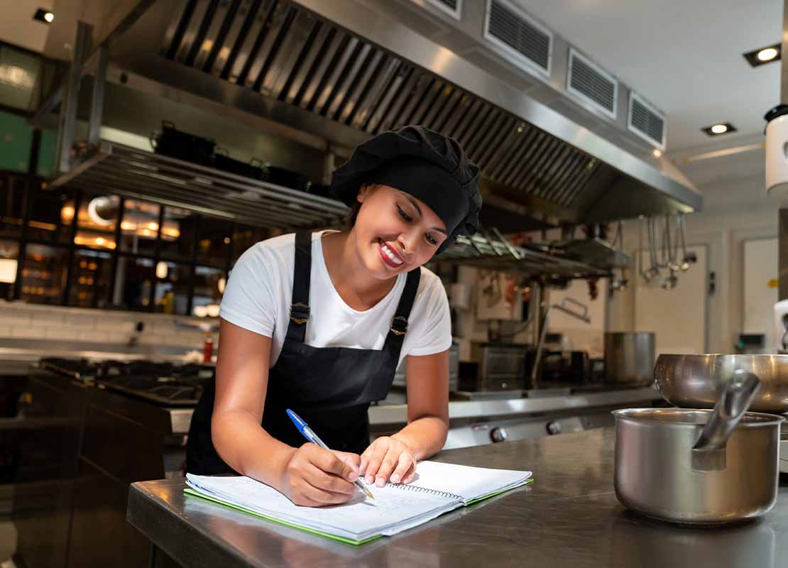 Una chef escribe las descripciones de los platos para el menú de restaurante