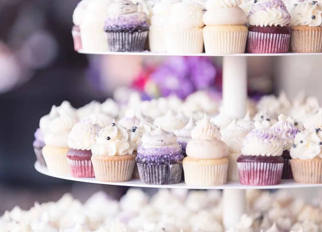 Estructura de varios niveles con cupcakes diferentes que hacen parte de una mesa de postres