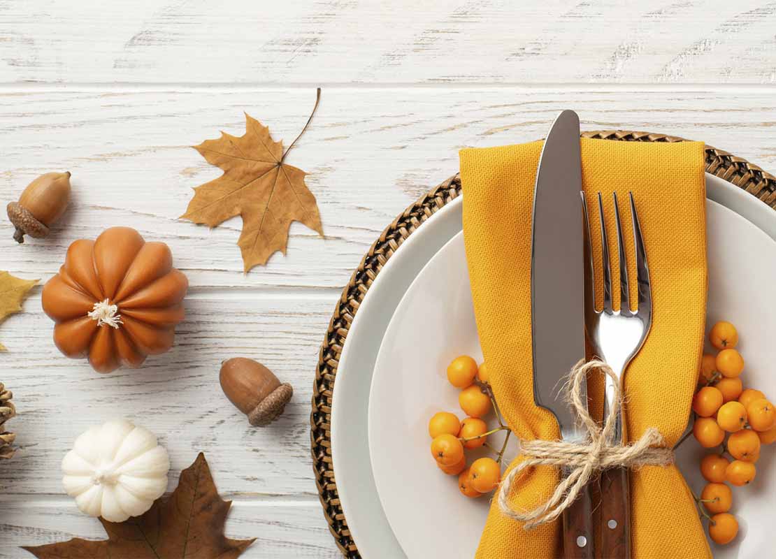 Mesa dispuesta con cubiertos sobre un plato y elementos de otoño en un restaurante temático de la temporada