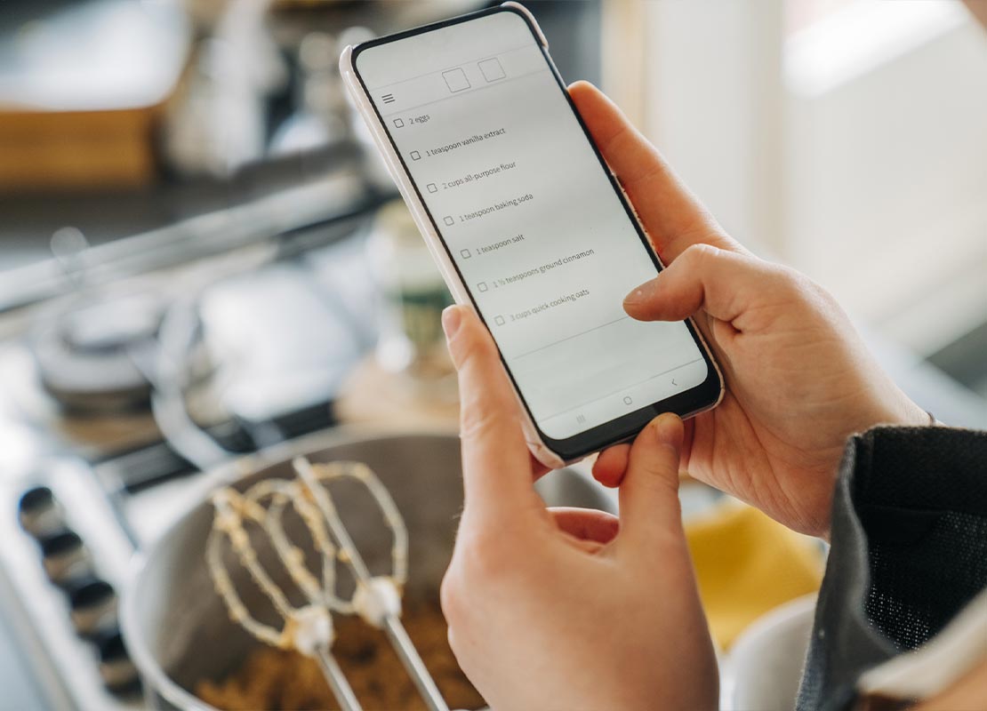 Chef en la cocina de un restaurante ingresando a sus redes sociales a través de su smartphone