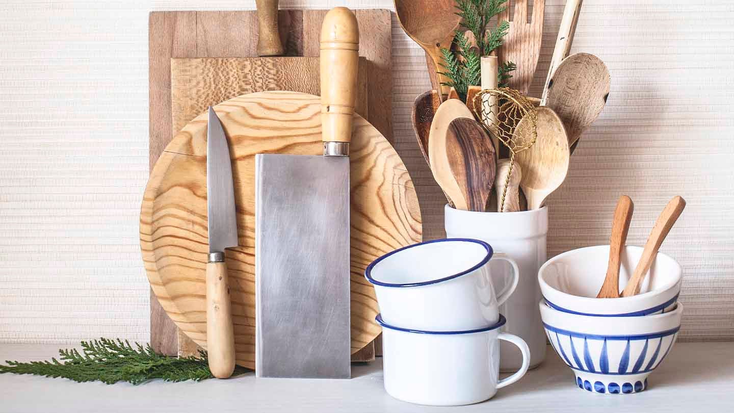 Utensilios de cocina en madera como diversas tablas de picar, cuchillos, cucharas, mezcladores, espátulas, tazas y pocillos