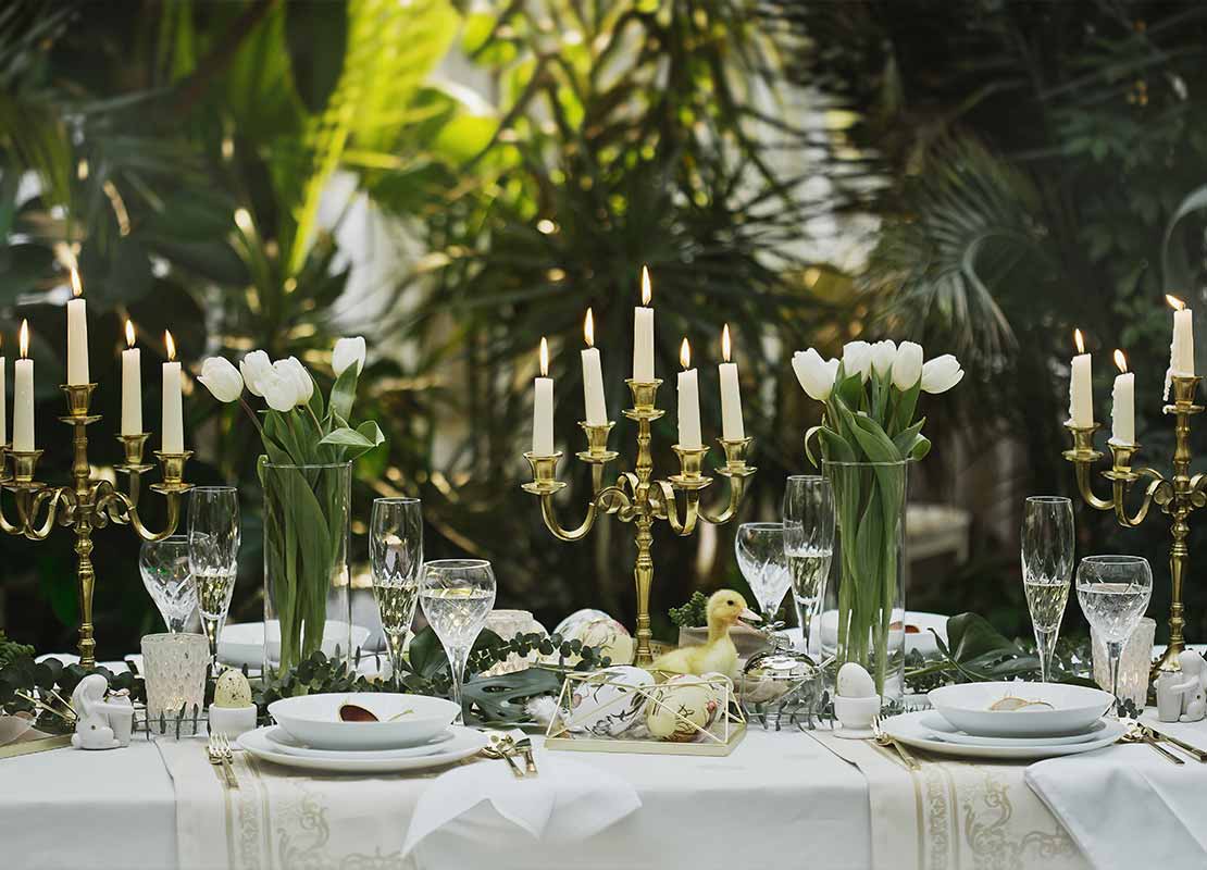 Mesa de restaurante con mantel blanco decorada con candelabros y velas