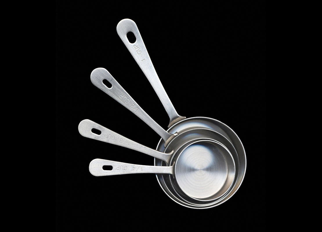 Utensilios de cocina esenciales como estas cuatro tazas medidoras de acero inoxidable colocadas una entre otra