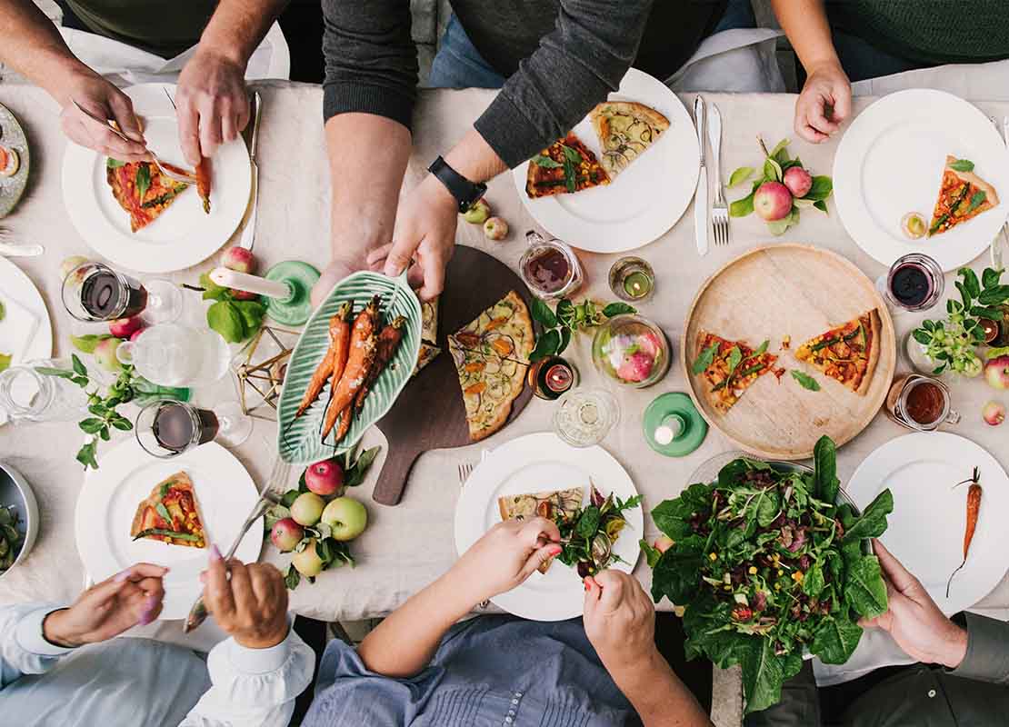Vista de una mesa con diversos platillos y alrededor personas tomando alimentos