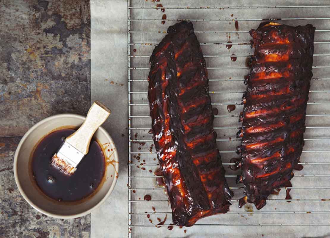 Costillas de cerdo glaseadas con una reducción de café servida en una taza con una brocha