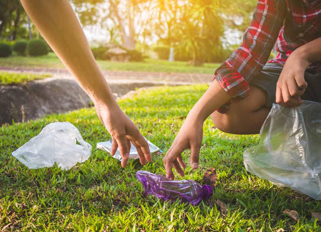 Personas recogiendo basura tirada sobre el césped en el Día de la Gastronomía Sostenible