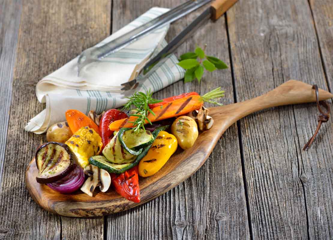 Ingredientes umami como verduras mixtas y hongos shiitake a la parrilla sobre una tabla de cortar