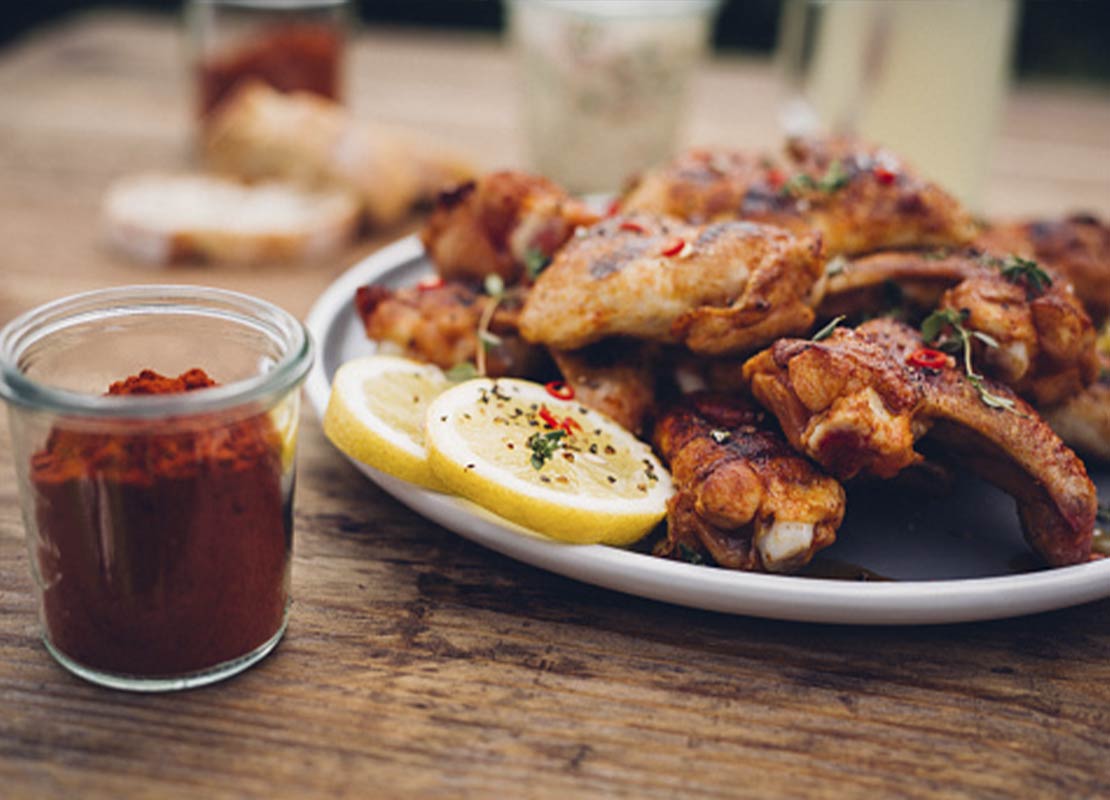 Plato de pollo asado picante y especiado, al lado un frasco de paprika, que hace parte de las food trends
