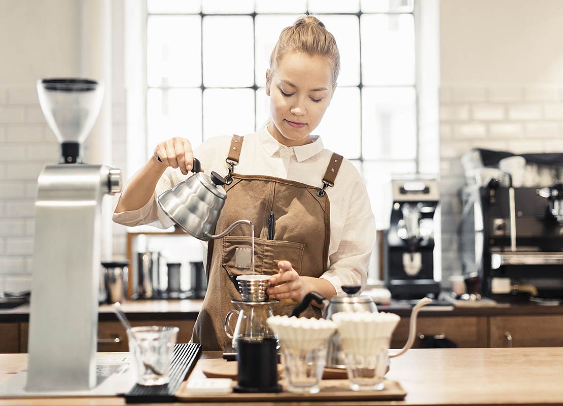 Barista utiliza herramientas como un dripper y tetera de agua caliente para preparar café filtrado