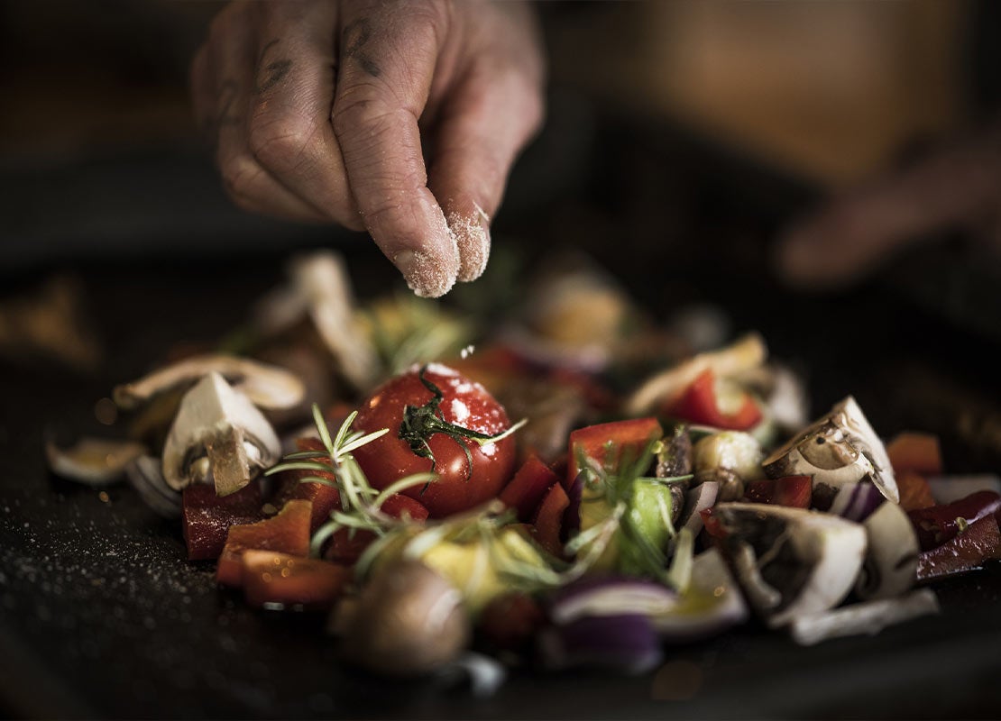 Mano agrega sal a una preparación plant based con vegetales y hongos que hace parte de las food trends