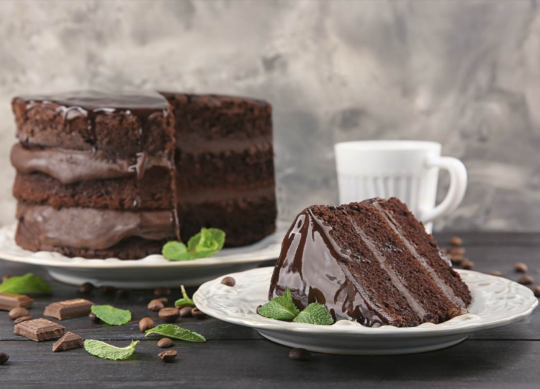 Una torta y un trozo servidos en platos, elaboradas con el chocolate para repostería de NESTLÉ®