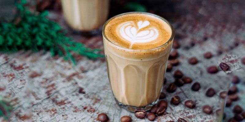 Dos vasos de café cortado rodeados de granos de café