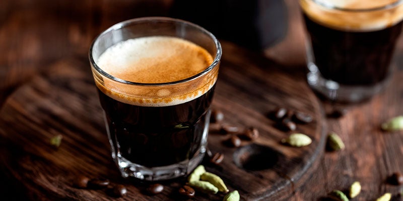 Shot de espresso en una copa de cristal sobre una repisa de madera