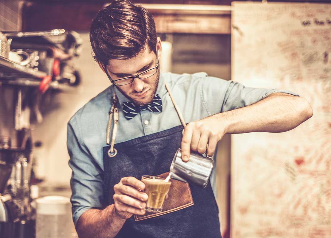 Barista preparando una bebida en una cafetería para su menú de café