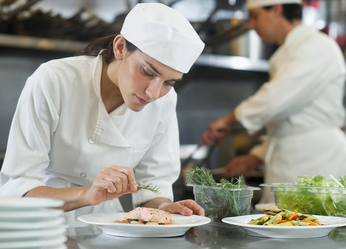 Chef decorando con especias un platillo para un menú de desayuno en una cocina comercial