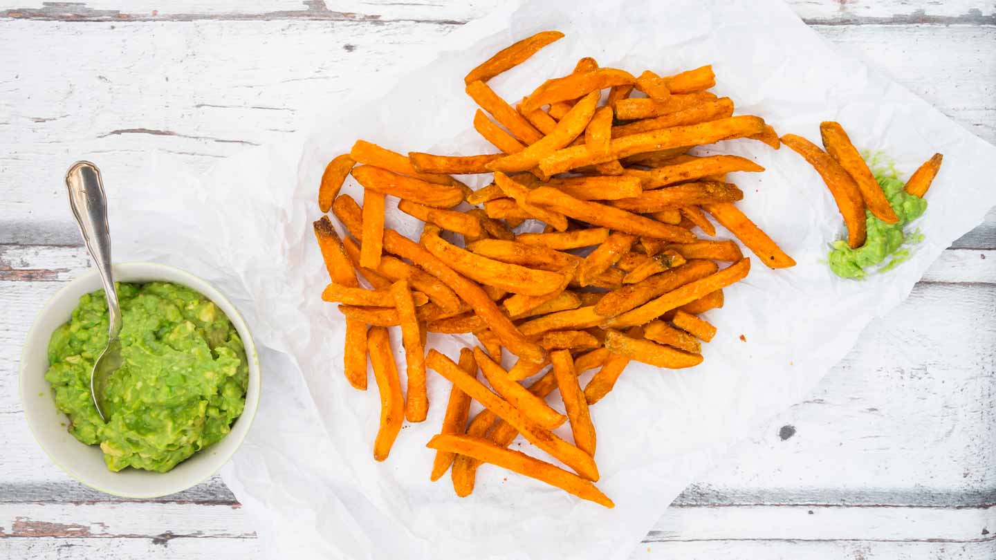 Plato de porcelana con papas fritas en bastones acompañadas de una taza de guacamole