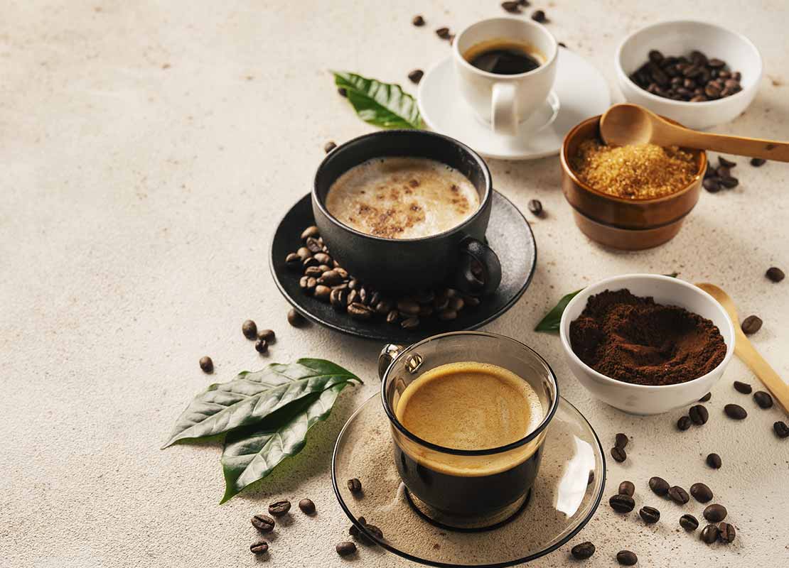 Tazas de café de gres, cerámica y cristal con bebidas calientes, azúcar y granos de café