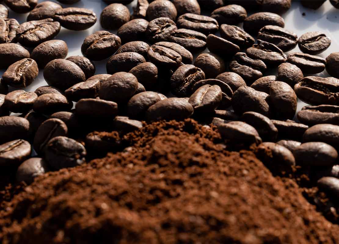 Sobre una mesa, café en grano y molido procesado por molinos de café