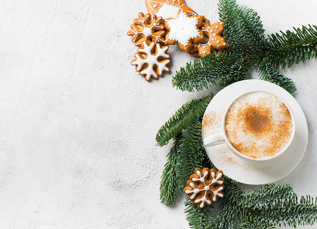 Taza de cappuccinno decorada con canela y galletas para coffee break navideño