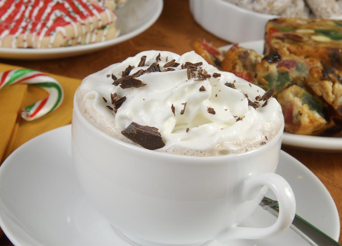 Taza de cappuccino decorada con crema batida y chocolate y preparada con los productos lácteos