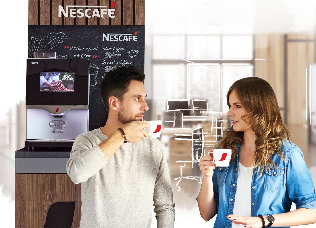 Hombre sostiene una revista y al fondo una máquina de café NESCAFÉ®, vasos y publicidad POP
