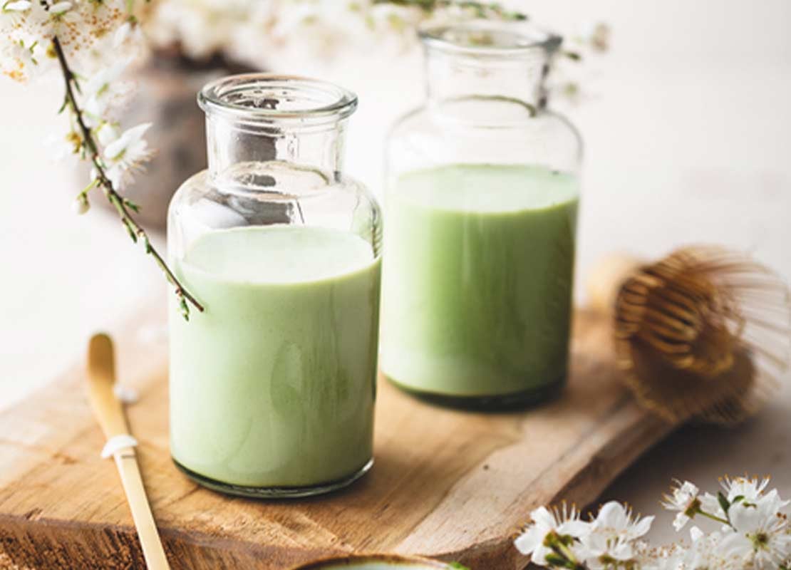 Dos frascos de cristal con té junto a flores blancas