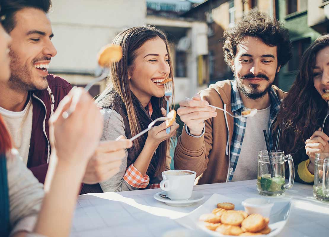 Compañeros de trabajo comparten alimentos y café en espacio de coffee break al aire libre