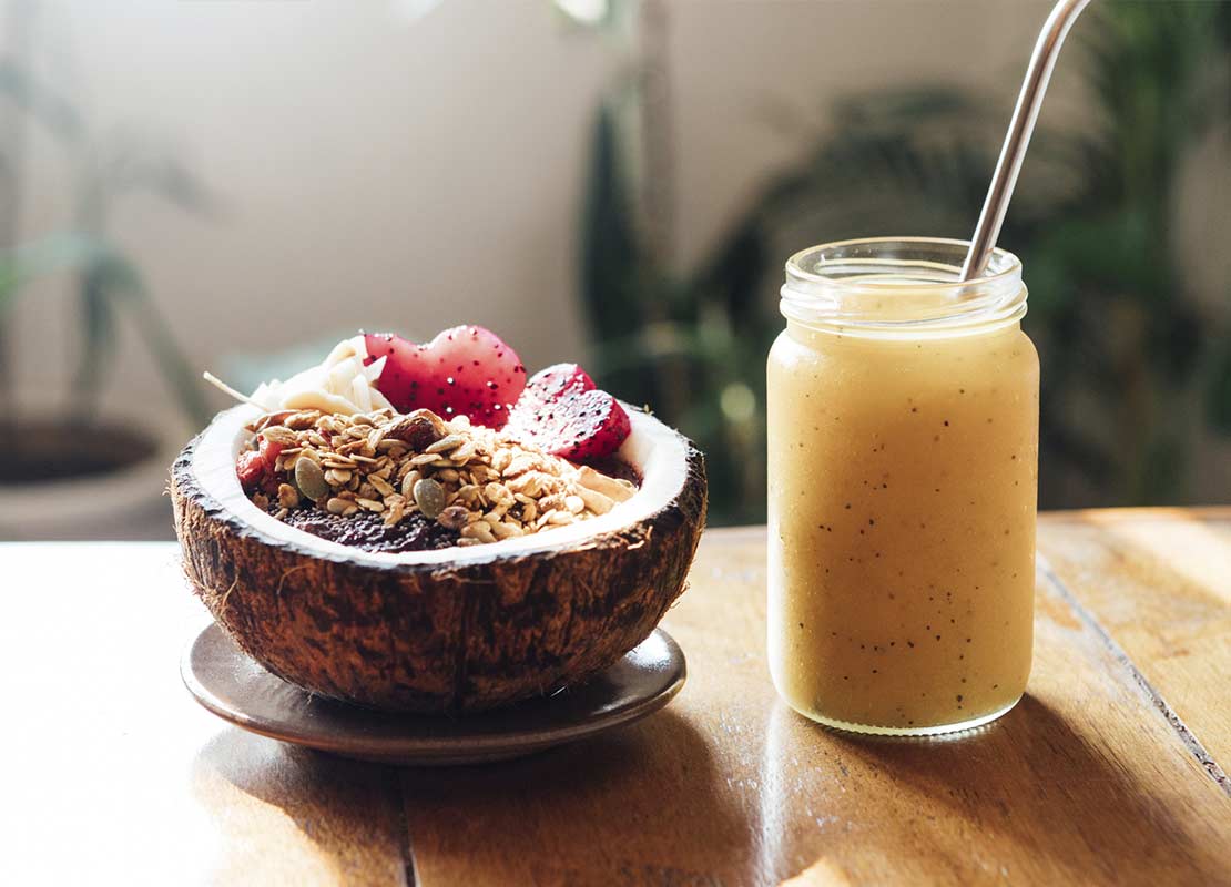 Cascarón de un coco con frutas y granola y batido de mango en una mesa para un brunch