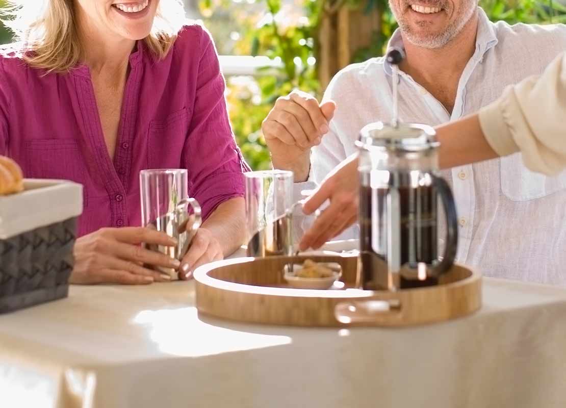 Método de preparación de café con prensa francesa sobre una mesa junto a una canasta de pan