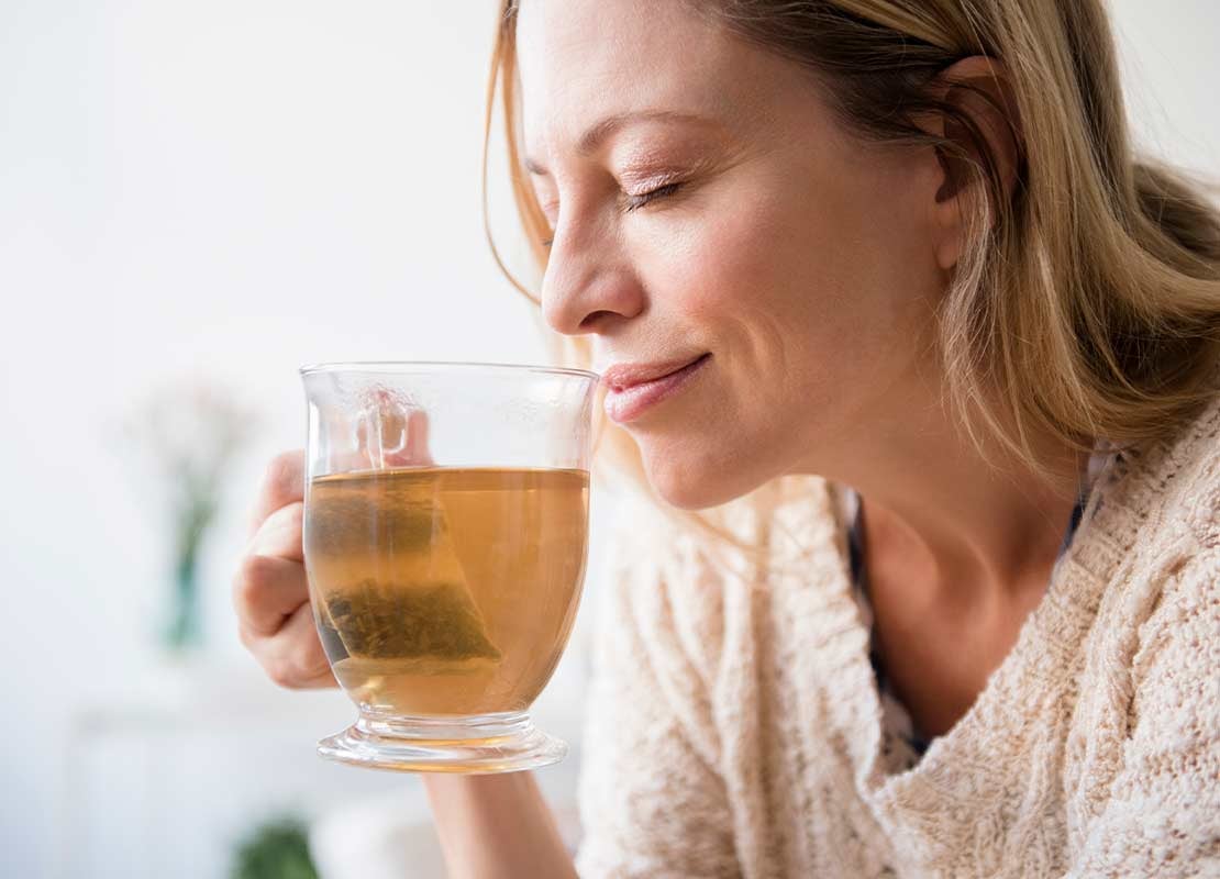 Mujer bebe plácidamente uno de los tipos de té e infusiones de NATURE’S HEART