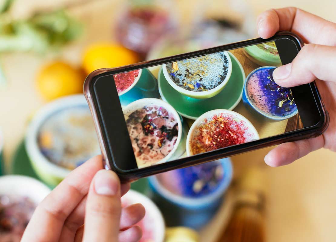 Persona tomando fotos de diferentes tipos de tés e infusiones ubicados sobre una mesa