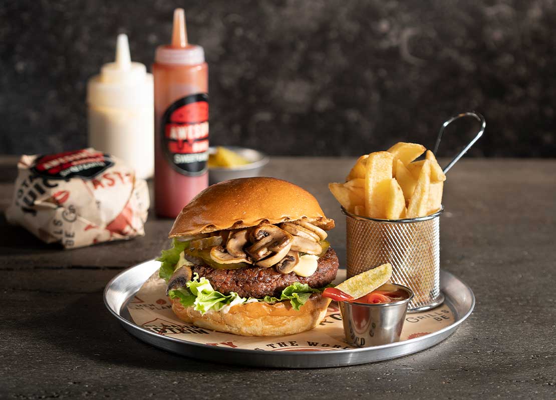 Hamburguesa elaborada con ingredientes de origen vegetal, papas y salsa sobre una bandeja