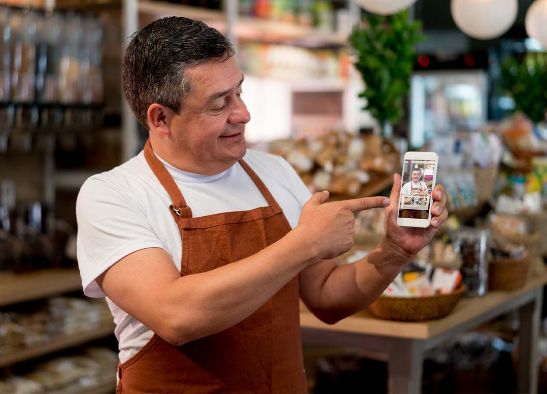 Barista en su negocio muestra en un smartphone el video creado para sus ofertas de Black Friday