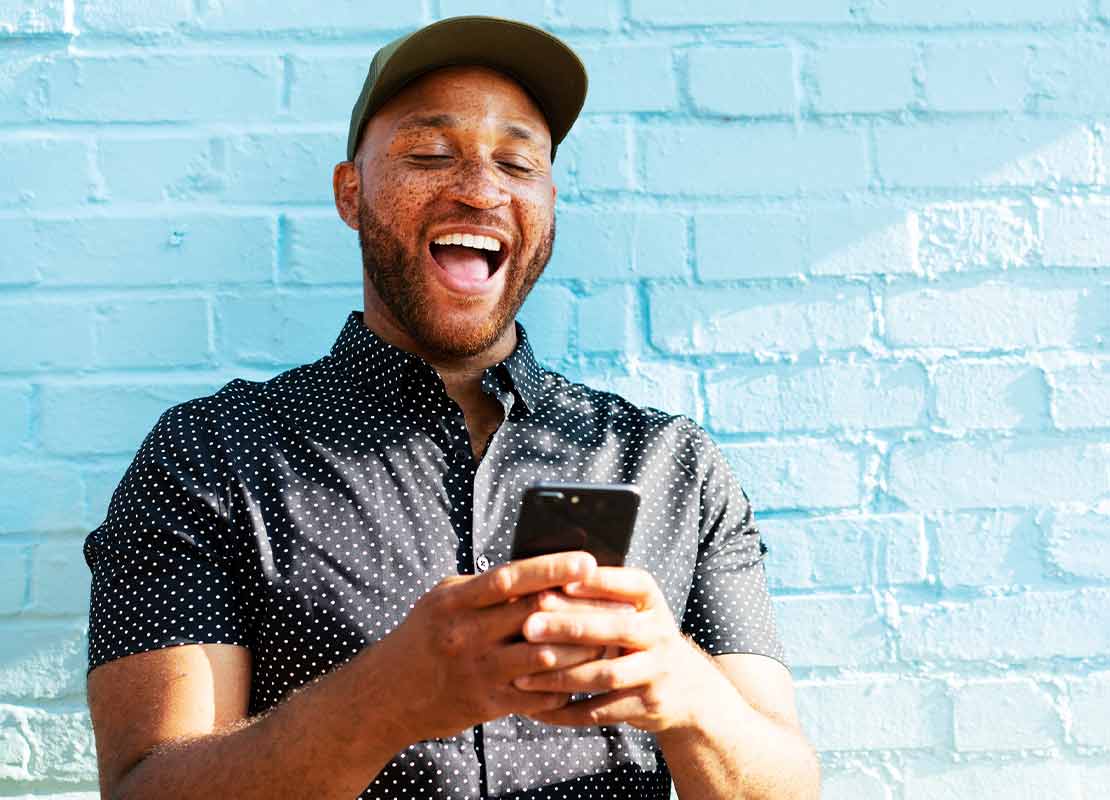 Hombre sonríe mientras observa su smartphone tras recibir publicidad personalizada de un restaurante