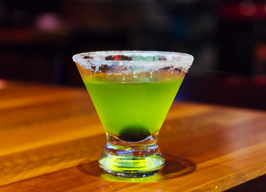 Michelada verde sin alcohol con borde de azúcar, servida en una copa de Martini sobre una mesa