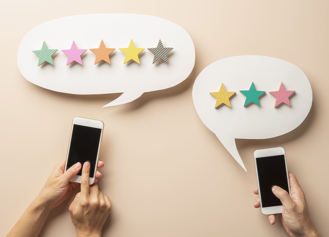 Manos tocan la pantalla de 2 celulares con burbujas de diálogo que contienen estrellas de calificación