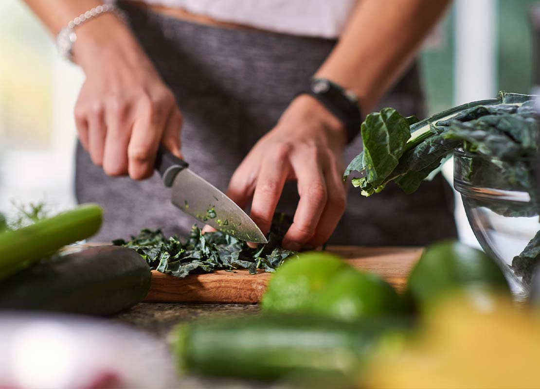Manos de un chef cortan hojas de verduras para aprovecharlas en recetas