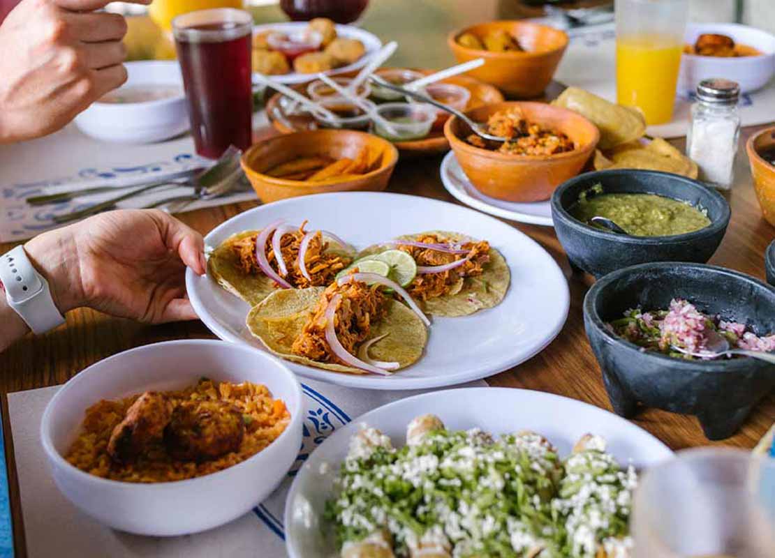 Familia comparte un almuerzo de comida mexicana con aderezos y bebidas en un hotel